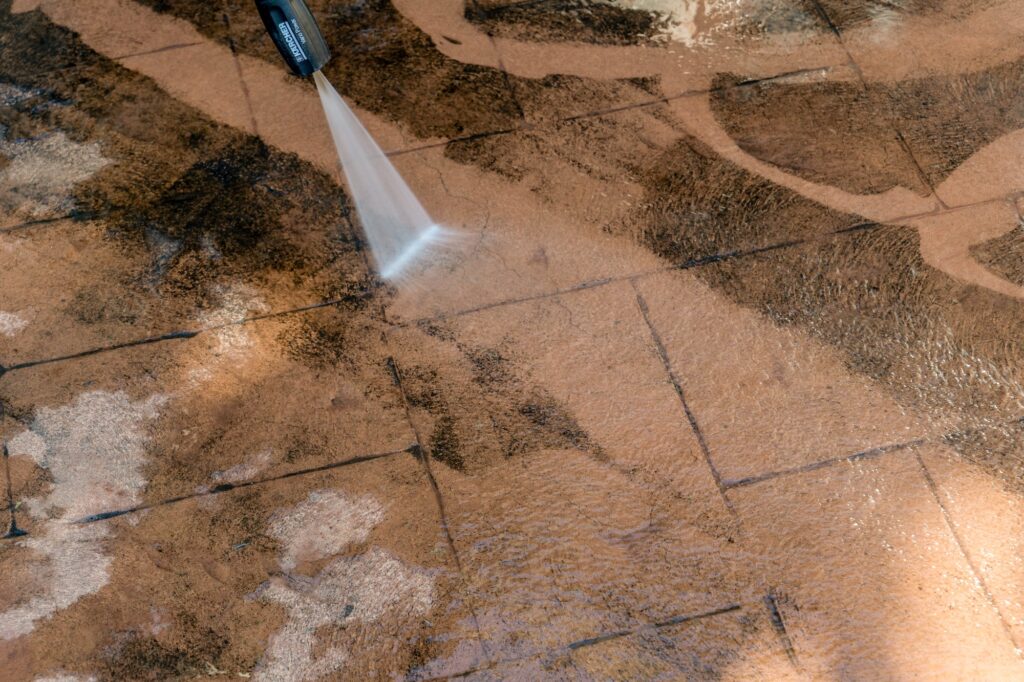 Washing dirty backyard tiles with high pressure cleaner. Spring clean up